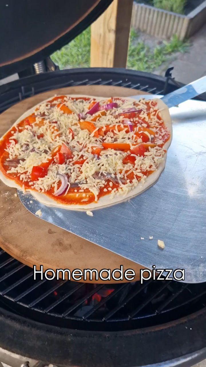 Pizza met tomatensaus, salami, ansjovis, paprika, cherry tomaten, rode ui en kaas